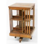 A late Victorian walnut and cross banded revolving bookcase, two tier each of four sections, raised