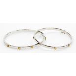 A pair of 9ct two coloured gold Cartier style bangles, set with screw decoration at intervals, each