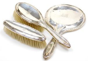 An Edward VII silver mounted three piece dressing table set, comprising mirror, hair brush and hand