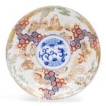 A Qing Dynasty late 19thC Imari dish, decorated with reserves of scholars in a garden, centrally wit