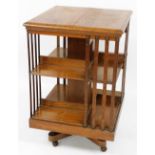 A late Victorian oak revolving bookcase, of two tier four section form, raised on an X framed base,
