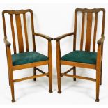 A pair of Arts and Crafts oak carved elbow chairs, with drop in seats, raised on tapering square leg