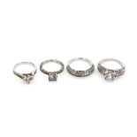Four silver dress rings, each stone set, comprising three solitaire rings and a half hoop eternity r