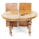 An Edwardian mahogany wind out dining table, with two additional leaves, raised on turned legs, bras