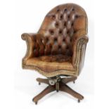 An early 20thC brown leather swivel armchair, with button back and seat.