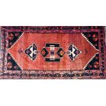 A Qashqai red ground rug, decorated with three central medallions, within repeating geometric border