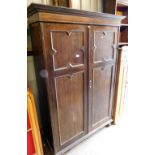 An early 20thC oak double wardrobe, the top with a moulded cornice above two panelled doors, on bun