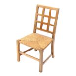 An early 20thC oak rush seated Arts and Crafts child's chair, with lattice back, 69cm high.