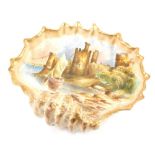 An early 20thC printed shell dish, decorated with a scene of Conway Castle with gilt highlights, ind