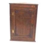 A 19thC oak hanging corner cabinet, with a single panel door and brass H hinges, 106cm high, 73cm wi