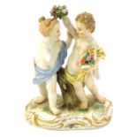 A 20thC Meissen figure group of two cherubs, fighting over a garland, polychrome decorated with gilt