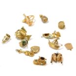 A group of 9ct gold charms, comprising fish with pearl, money bag, bird cage, ship, drum, bullfighti