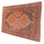 A Persian rug, on a brown and burnt orange ground, with two central medallions and geometric border,