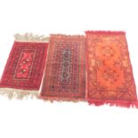 Three rugs, comprising one with two central medallions, on a red ground, 59cm x 44cm, a rug with two