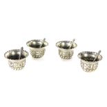 A set of George V silver salts and spoons, each with a flared rim and embossed floral design, London