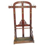 A Victorian mahogany hall stand, with arched top with applied brass hooks, umbrella well base on bun