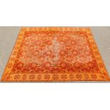 An Oriental design rug, on an orange ground with medallions and flowers, and spotted border, 210cm x
