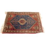 A Persian rug, in blue, red and cream, with a central medallion and four narrow borders, 95cm x 68cm
