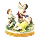 A porcelain figure group, formed as three children playing musical instruments, on a naturalistic ba