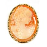 A shell cameo brooch, of a neo-classical design female with curled hair and flowers, in a flared gol