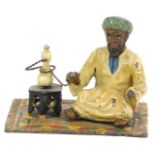 A Bergman style cold painted spelter figure, seated on a Persian carpet, with oil lamp, 7cm high, 8c