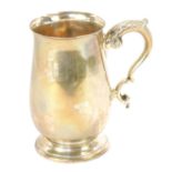 An Elizabeth II silver tankard, of plain form with acanthus leaf scroll handle, on a stepped foot, B