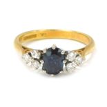 An 18ct gold sapphire and diamond dress ring, the oval cut sapphire in eight claw setting, flanked b