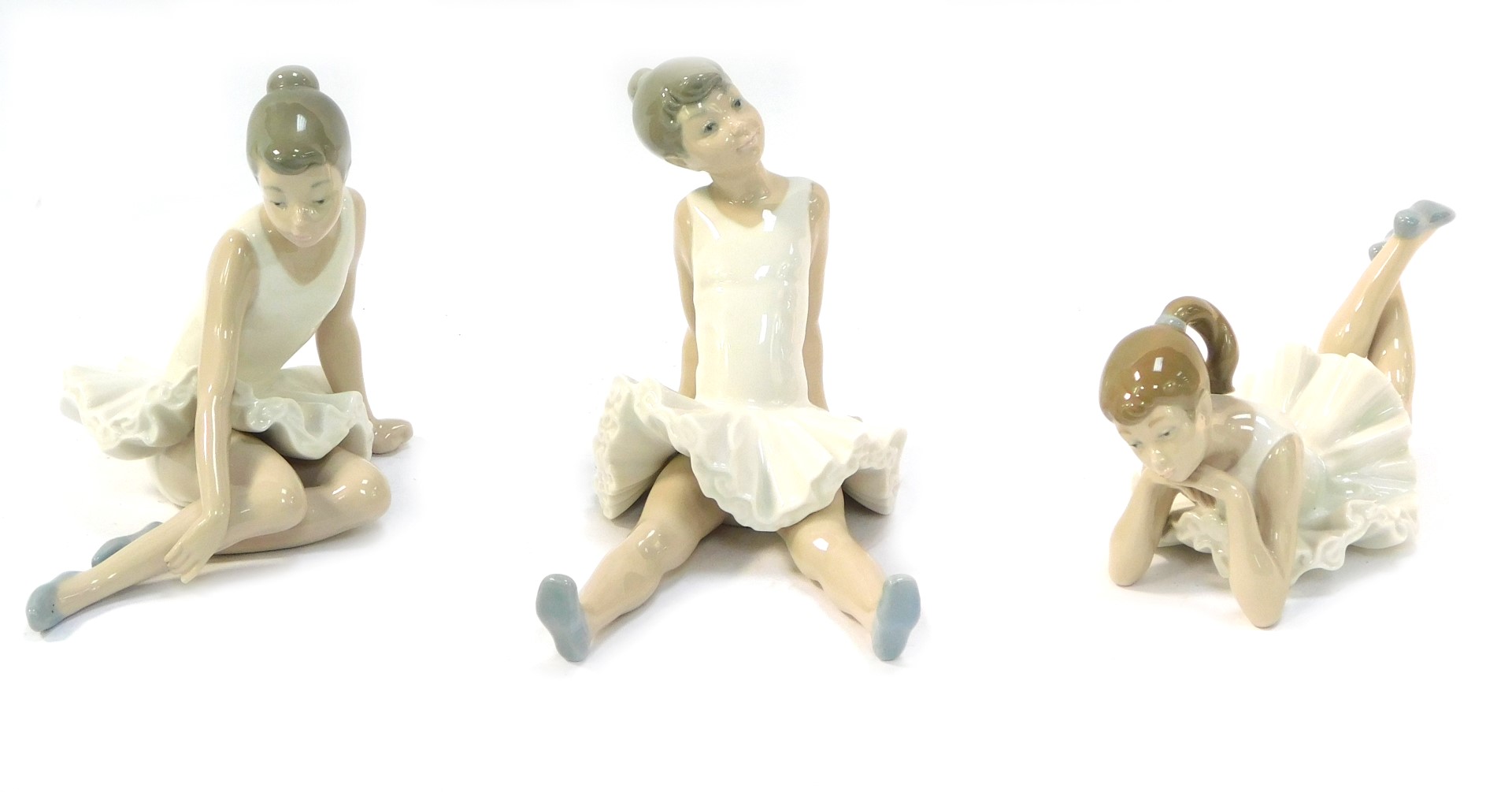 Three Nao pottery figures of seated ballerinas, marked beneath, 14cm high. (3)