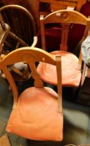 Two Victorian oak framed lounge chairs, each with a pink upholstered seat and carved daisy back. (2)