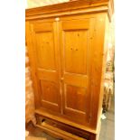 A pine two door wardrobe, the two paneled doors above single drawer with moulded cornice top, on bra