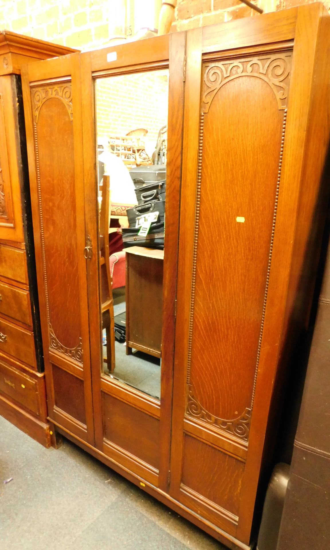 An Edwardian carved oak wardrobe, with single glazed door and two carved panels, on tapered legs.