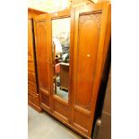 An Edwardian carved oak wardrobe, with single glazed door and two carved panels, on tapered legs.