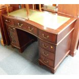 A mahogany reproduction desk, with curved front and green leather inset top, above an arrangement of