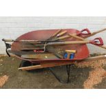 A metal wheelbarrow, and various tools to include saws, forks, shearers and walking cane. (a quantit