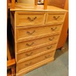 A light wood effect dressing chest, of two short and four long drawers.