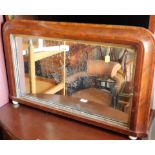 A Victorian walnut overmantel mirror, with ceramic bun feet.