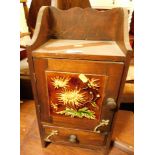 An oak smokers cabinet, with majolica tile insert decorated with sunflowers.