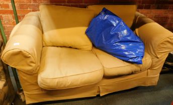 A two seater sofa, with light yellow covers and some spare covers.