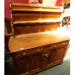 A carved light oak sideboard, with dresser rack back above two drawers and two cupboard doors, termi