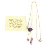 An Art Nouveau drop pendant, set with four amethyst coloured stones and attached to a slender link n