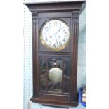 A mid 20thC oak cased wall clock, the 17cm diameter dial with Arabic numerals, flanked by acanthus c