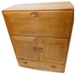 An Ercol light elm secretaire, the fall front, two doors and a drawer, each with shaped and turned w