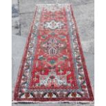 A vintage washed red ground Persian runner, in traditional medallion pattern, 310cm x 115cm.