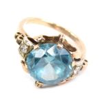 A dress ring, claw set with a large blue zircon, the part pierced shank inset with two diamonds, unm