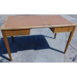 A 1950/60's utility MOD oak writing table, with a brown leather inset above an arrangement of drawer