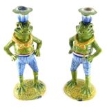 A pair of Continental tin glazed earthenware frog candlesticks, each vibrantly decorated predominant