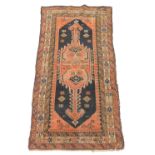 A Persian rug, with a central orange pole medallion, on a black ground with three geometric borders,