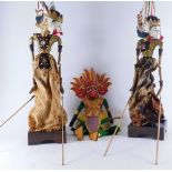 A pair of Eastern puppet figures, with articulated limbs on wooden bases, profusely decorated in col