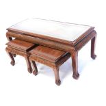 A nest of three oriental hardwood tables, each carved with figures, trees, etc. on shaped supports,