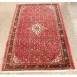 A Persian carpet, with an all over design of roundels and other geometric devices, on a red ground,